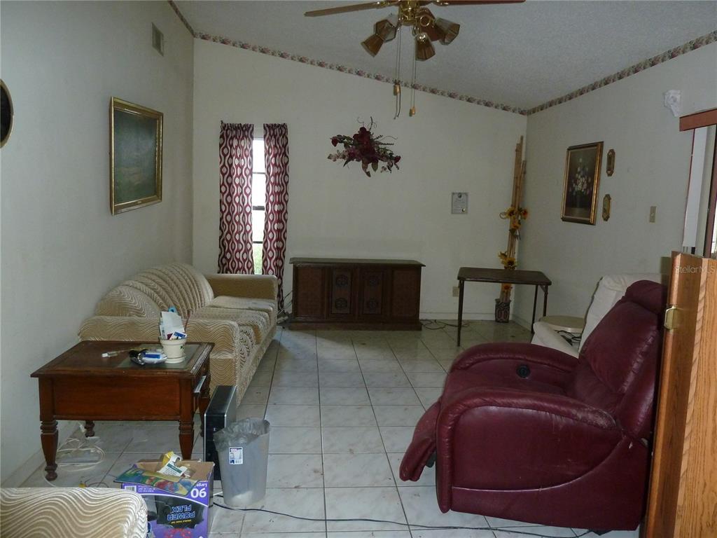 A living room features a beige sofa, a red recliner, tile flooring, and a ceiling fan — 16224 SAWGRASS CIRCLE, TAMPA, FL