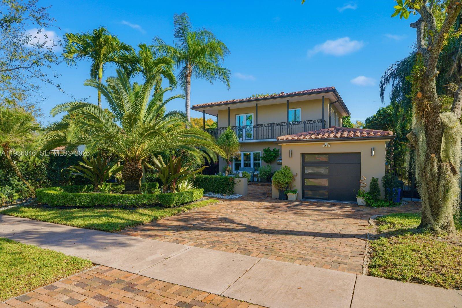 A two-story house with a brick driveway, attached garage, and palm trees in the front yard — 430 Candia Ave, Coral Gables FL 33134, CORAL GABLES, FL
