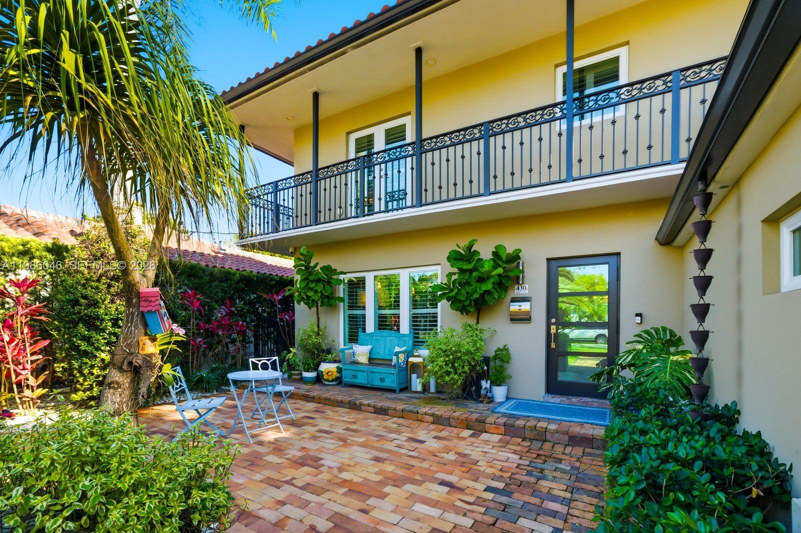 A two-story house with a brick patio, a blue bench, and a second-floor balcony — 430 Candia Ave, Coral Gables FL 33134, CORAL GABLES, FL