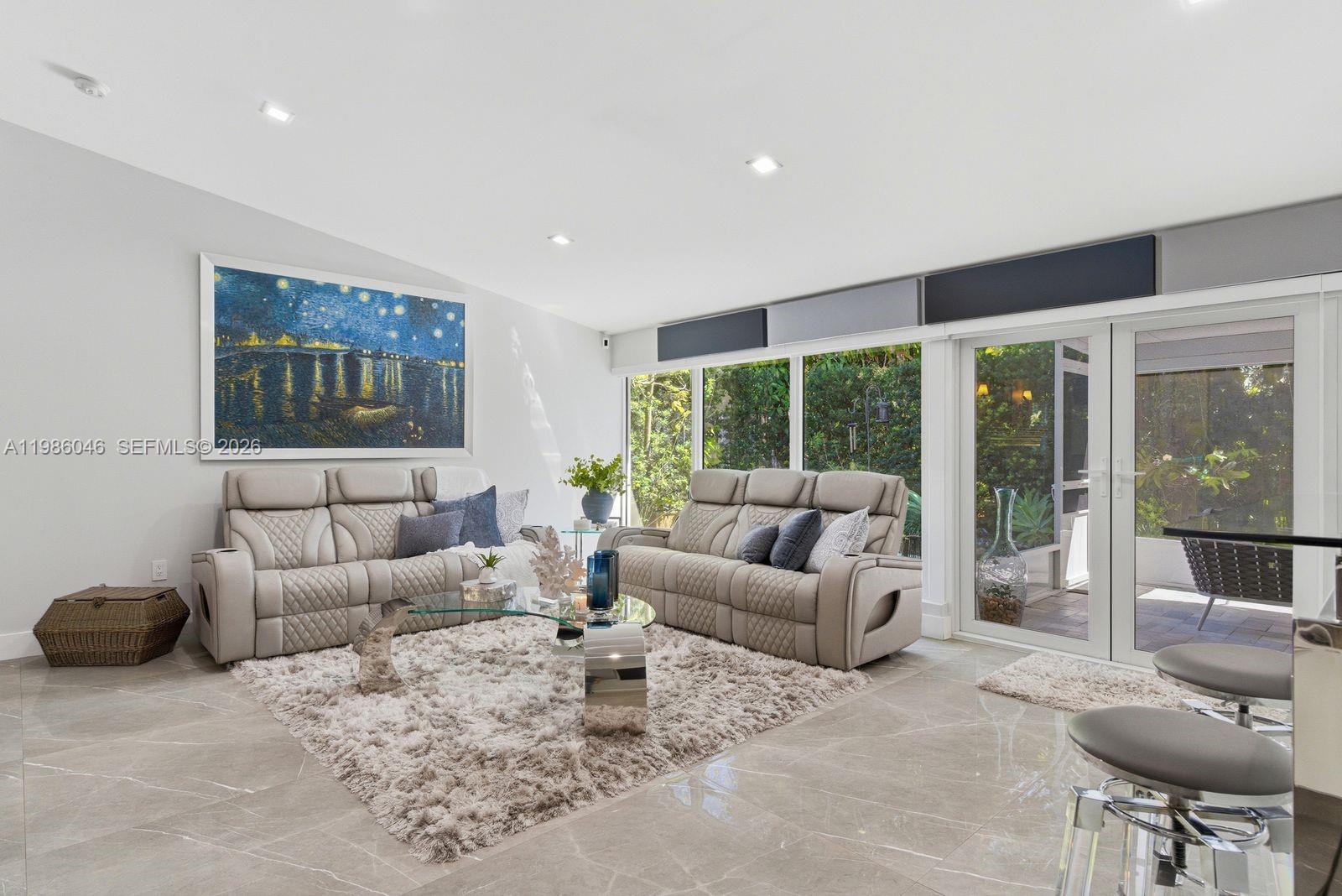 A living room features two beige sofas, a glass coffee table, and large sliding glass doors — 430 Candia Ave, Coral Gables FL 33134, CORAL GABLES, FL