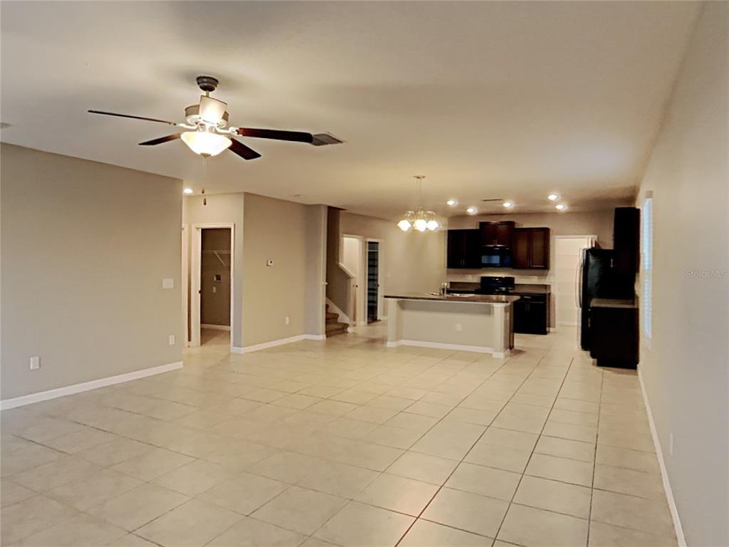 An open-concept living area features tile flooring, a ceiling fan, and a kitchen with dark cabinets — 4436 ETERNAL PRINCE DRIVE, SUN CITY CENTER, FL