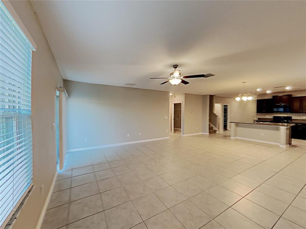 An open-concept living area features tile flooring, a ceiling fan, and an adjacent kitchen — 4436 ETERNAL PRINCE DRIVE, SUN CITY CENTER, FL