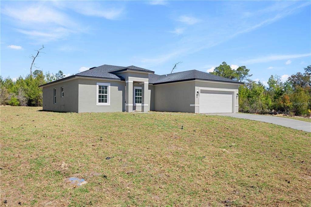 A single-story house with a beige stucco exterior, a two-car garage, and a grassy yard — 16753 SW 29TH TERRACE, OCALA, FL