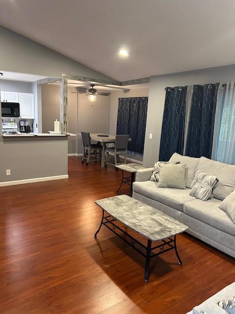 A living room with hardwood floors, a gray sofa, and an adjacent dining area — 815 W BOYNTON BEACH Boulevard # 202, Boynton Beach FL 33426, BOYNTON BEACH, FL