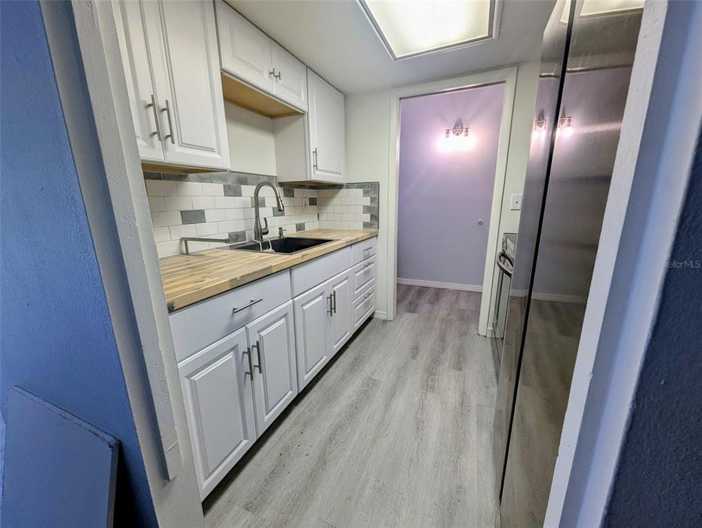 A galley kitchen features white cabinets, a butcher block countertop, and a subway tile backsplash — 2366 E MALL DRIVE UNIT 313, FORT MYERS, FL