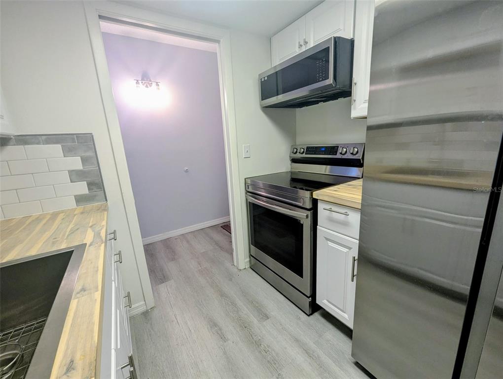 A kitchen features stainless steel appliances, white cabinets, and wood-look countertops — 2366 E MALL DRIVE UNIT 313, FORT MYERS, FL