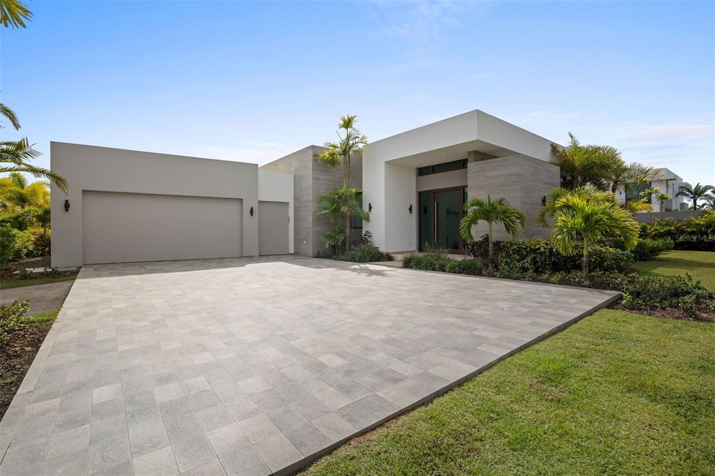 A modern single-story house with a paved driveway, flat roof, and stone-textured exterior walls — 63 THE ISLES AT DORADO BEACH, DORADO, PR