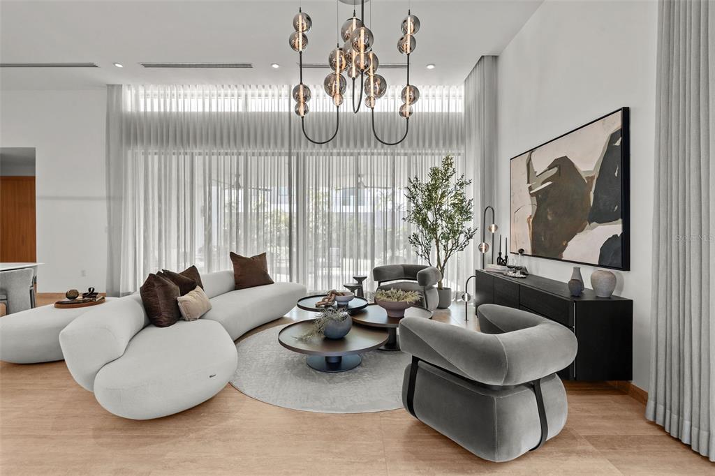 A modern living room features a curved sofa, two armchairs, nested coffee tables, and a chandelier — 63 THE ISLES AT DORADO BEACH, DORADO, PR