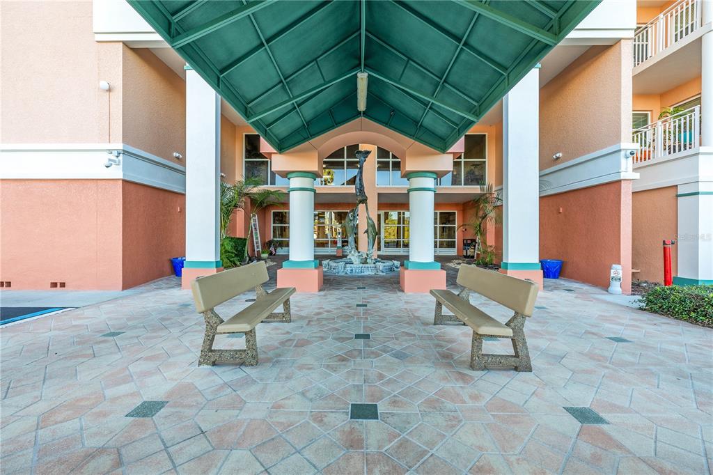 An outdoor entrance features a green metal awning, two benches, and a central dolphin fountain — 4516 SEAGULL DRIVE UNIT 805, NEW PORT RICHEY, FL