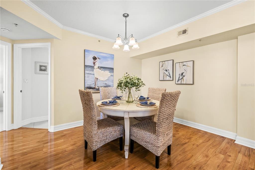 A dining room features a round white table, four wicker chairs, and a chandelier — 4516 SEAGULL DRIVE UNIT 805, NEW PORT RICHEY, FL