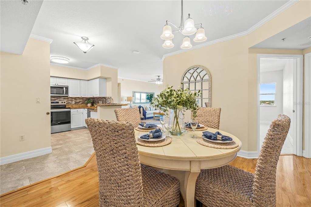 A dining area with a round table and woven chairs opens into a kitchen — 4516 SEAGULL DRIVE UNIT 805, NEW PORT RICHEY, FL