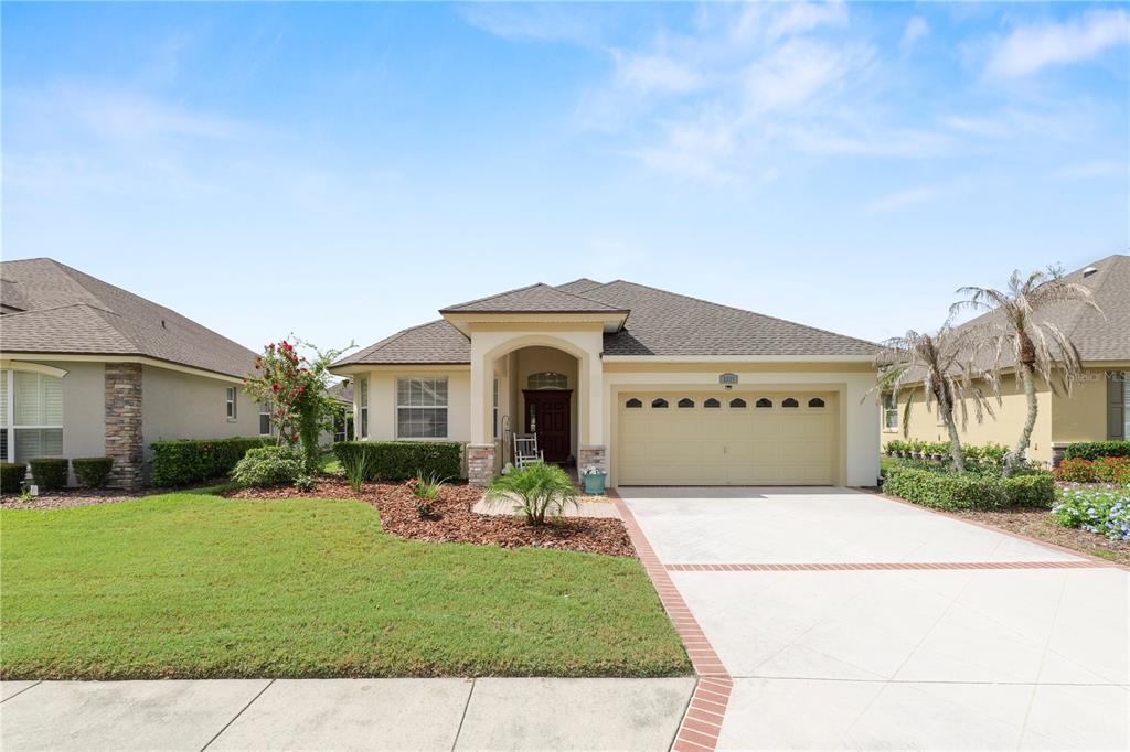 A single-story house with a beige stucco exterior, a two-car garage, and a landscaped yard — 2356 LAKE JAMES WAY, LAKELAND, FL