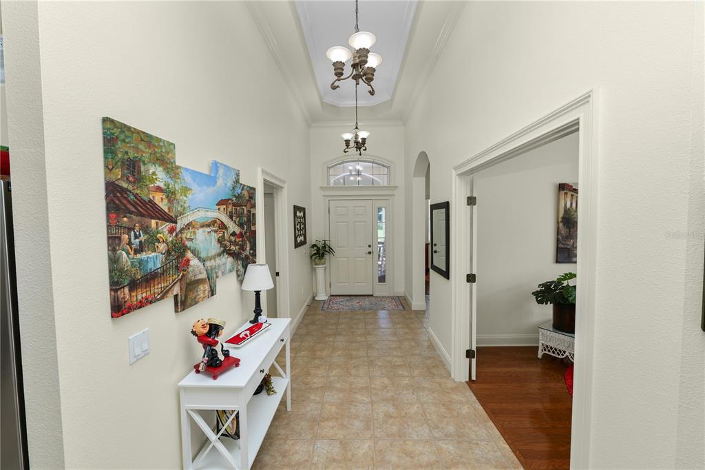 A tiled entryway features a white console table, wall art, and a chandeliered vaulted ceiling — 2356 LAKE JAMES WAY, LAKELAND, FL