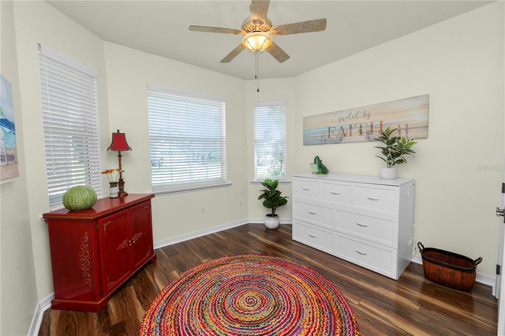 A room with wood-look flooring, a colorful circular rug, a white dresser, and a red cabinet — 2356 LAKE JAMES WAY, LAKELAND, FL