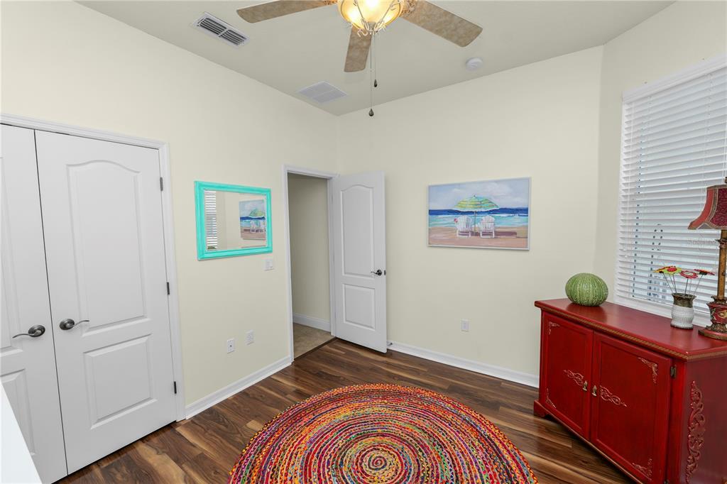A bedroom with wood-look flooring, a colorful round rug, a red cabinet, and a ceiling fan — 2356 LAKE JAMES WAY, LAKELAND, FL