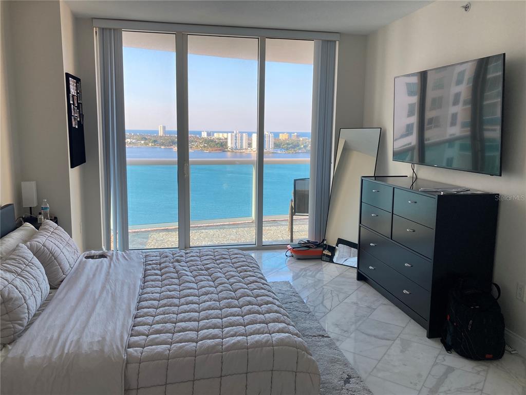 A bedroom with a bed, dresser, wall-mounted television, and floor-to-ceiling windows overlooking the ocean — 231 RIVERSIDE DRIVE UNIT 1504-1, DAYTONA BEACH, FL