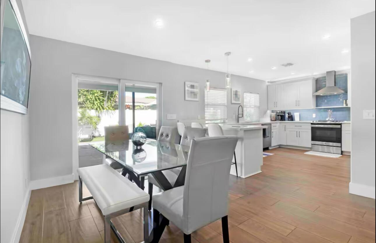 A dining area with a glass table and chairs opens to a kitchen with white cabinets — 623 Jaeger Drive, Delray Beach FL 33444, DELRAY BEACH, FL