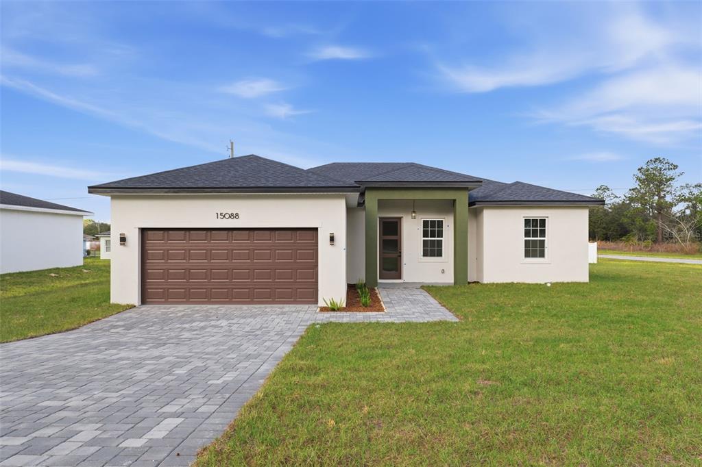 A single-story house with a white stucco exterior, a brown garage door, and a paved walkway — 15088 SW 51ST AVENUE, OCALA, FL