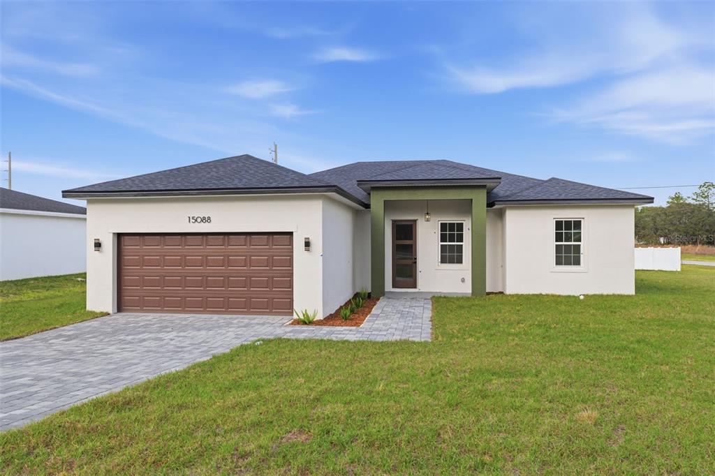 A paved walkway leads to the front entrance of a house with a green porch — 15088 SW 51ST AVENUE, OCALA, FL