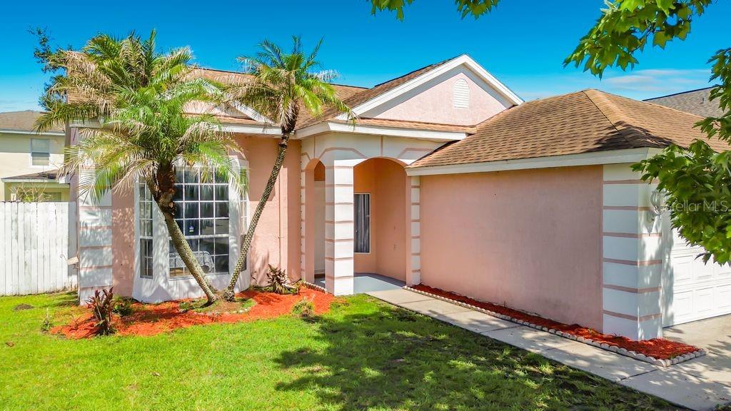 A single-story house with peach stucco walls, a brown shingled roof, and a palm tree — 2079 SHANNON LAKES BOULEVARD, KISSIMMEE, FL