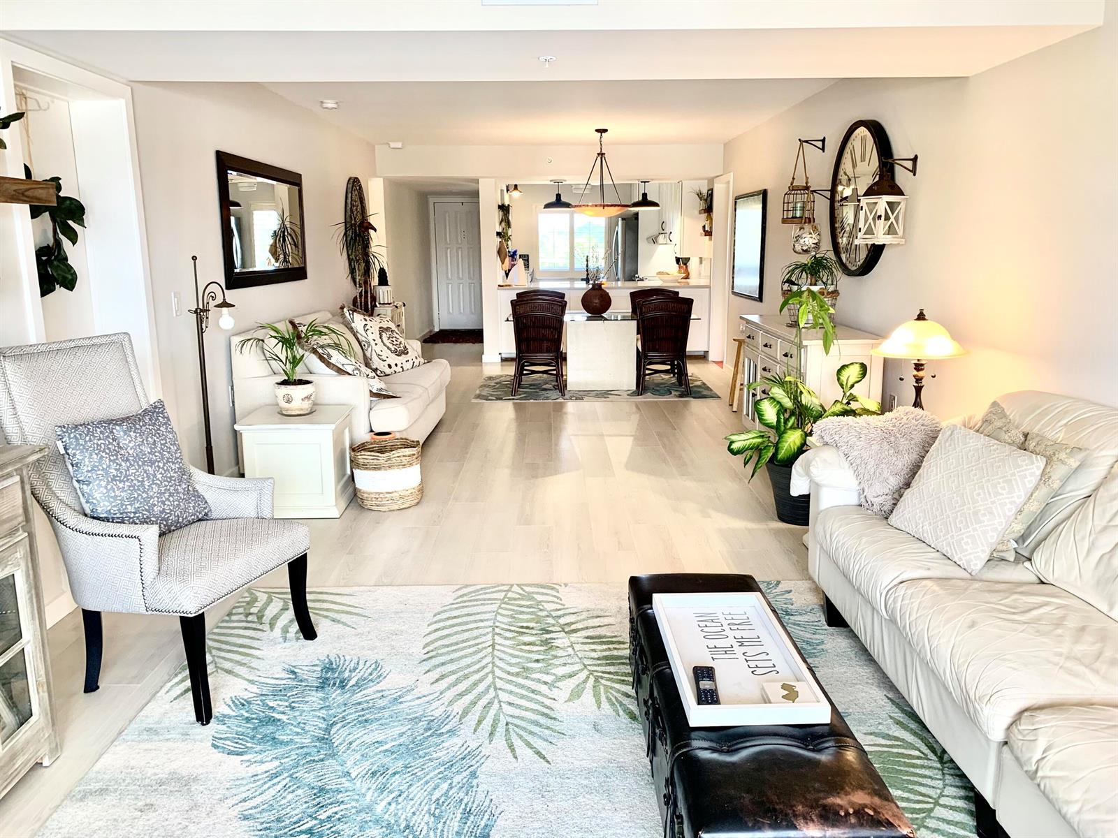 A bright living room features a palm-leaf rug, light wood floors, and a dining area — 1401 Tidal Pointe Boulevard # 406, Jupiter FL 33477, JUPITER, FL