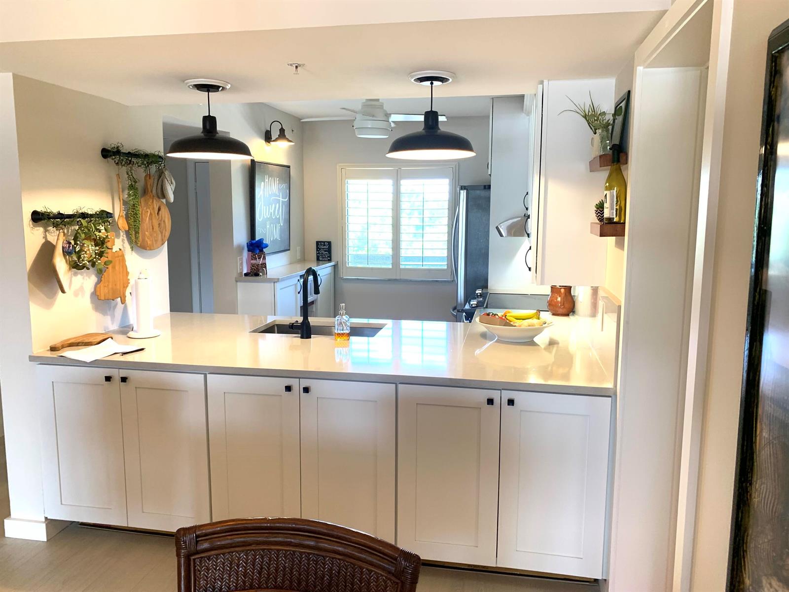 A kitchen features white cabinets, a quartz countertop, a sink, and two black pendant lights — 1401 Tidal Pointe Boulevard # 406, Jupiter FL 33477, JUPITER, FL