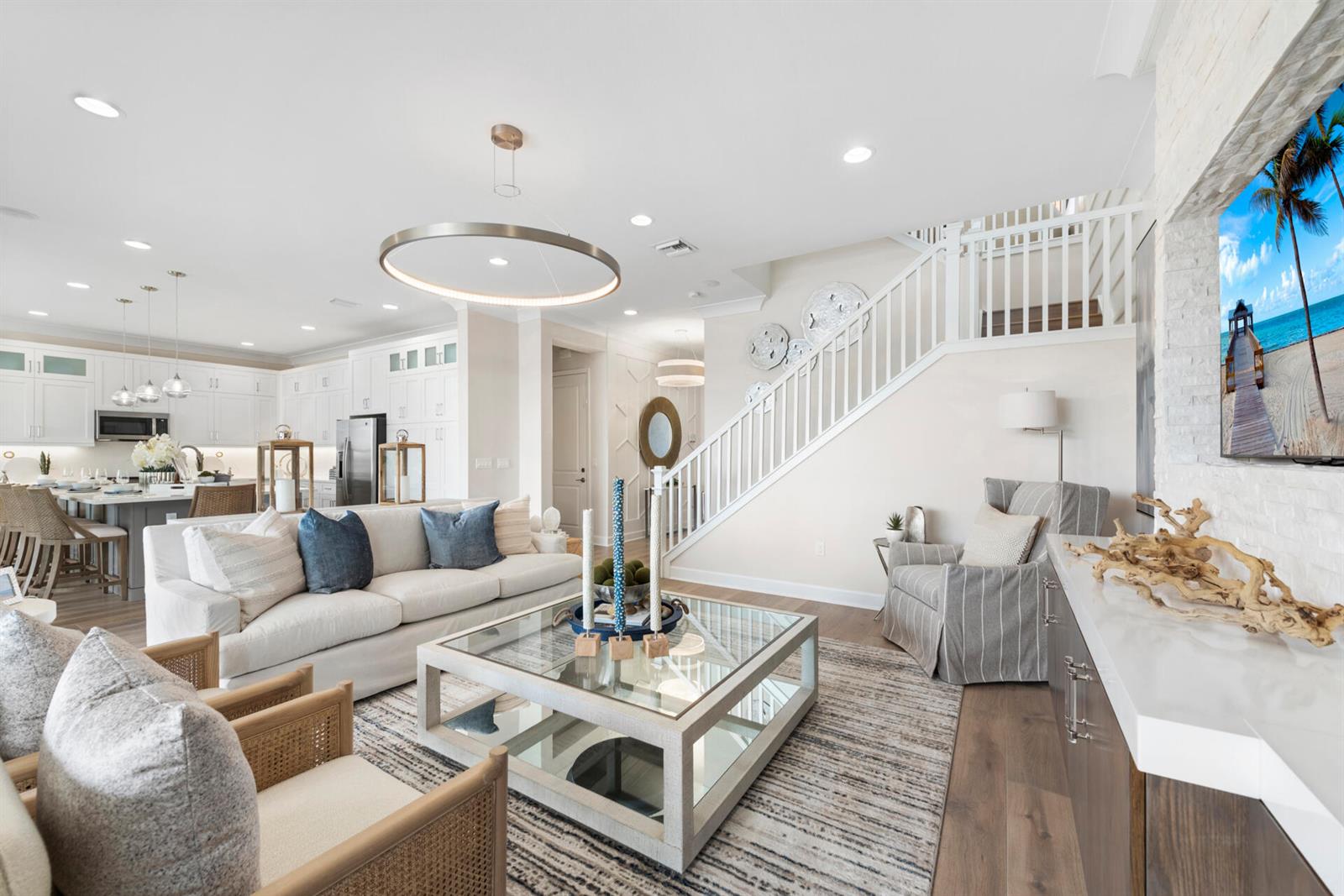 A bright living room features a white sofa, glass coffee table, and staircase — 419 41st Street, West Palm Beach FL 33407, WEST PALM BEACH, FL