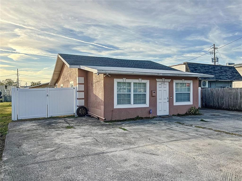 A single-story, peach-colored house with a concrete driveway and a white vinyl fence — 1109 5TH STREET SW, WINTER HAVEN, FL