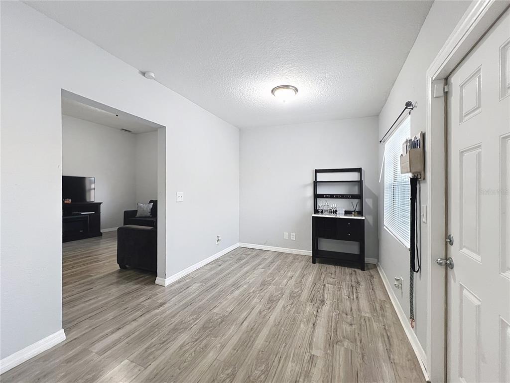 A room with light gray walls, wood-look flooring, a black shelving unit, and a doorway — 1109 5TH STREET SW, WINTER HAVEN, FL
