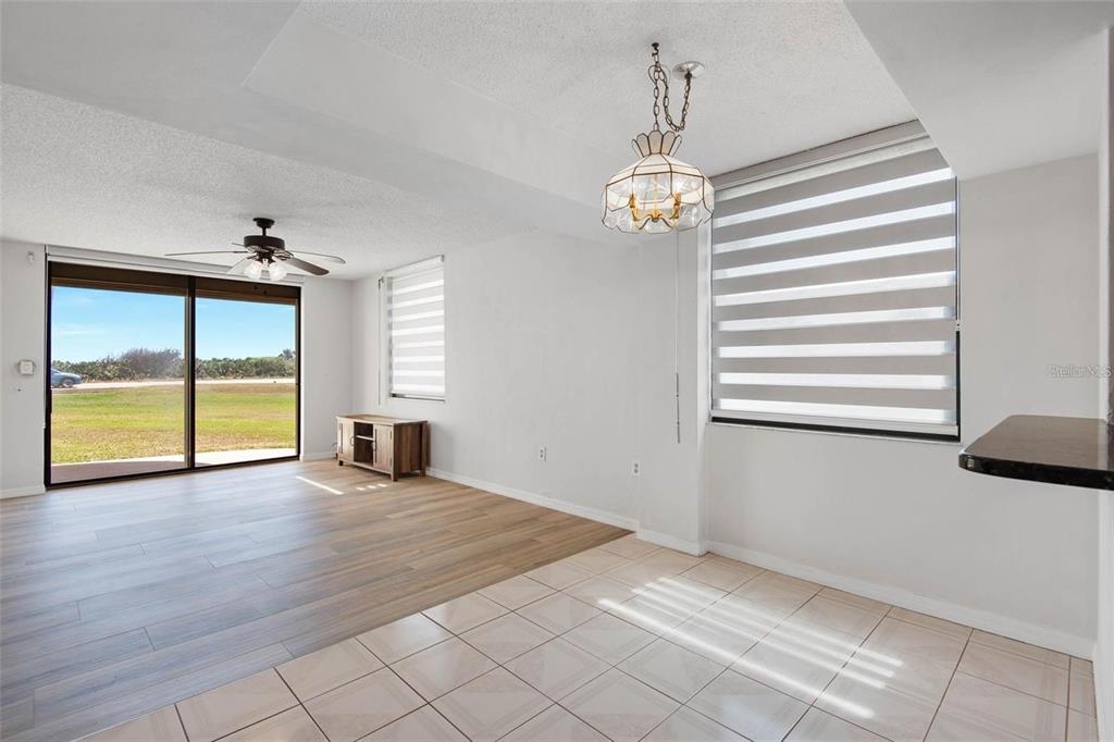A living and dining area features wood-look flooring, tile, a ceiling fan, and sliding doors — 3360 OCEAN SHORE BOULEVARD UNIT 1030, ORMOND BEACH, FL