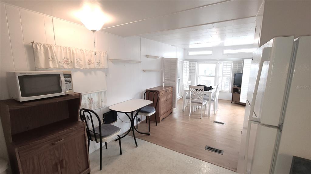 A kitchen and dining area with white walls, light wood flooring, and a small table — 4851 W GANDY BOULEVARD UNIT B4 L32, TAMPA, FL