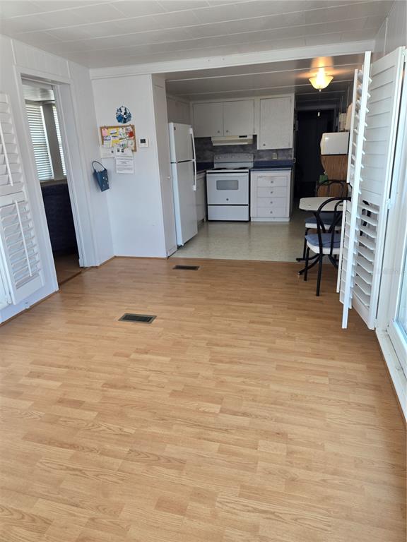 A kitchen with white appliances and cabinets opens into a living area with wood flooring — 4851 W GANDY BOULEVARD UNIT B4 L32, TAMPA, FL