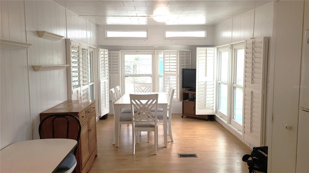 A dining room with light wood flooring, white paneled walls, and a white dining set — 4851 W GANDY BOULEVARD UNIT B4 L32, TAMPA, FL