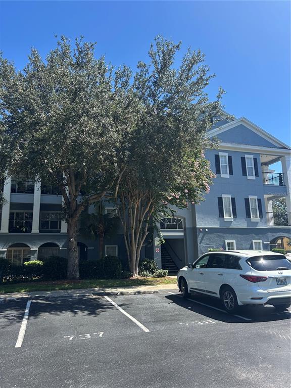 A white SUV is parked in front of a blue multi-story apartment building with trees — 3621 CONROY ROAD UNIT 738, ORLANDO, FL
