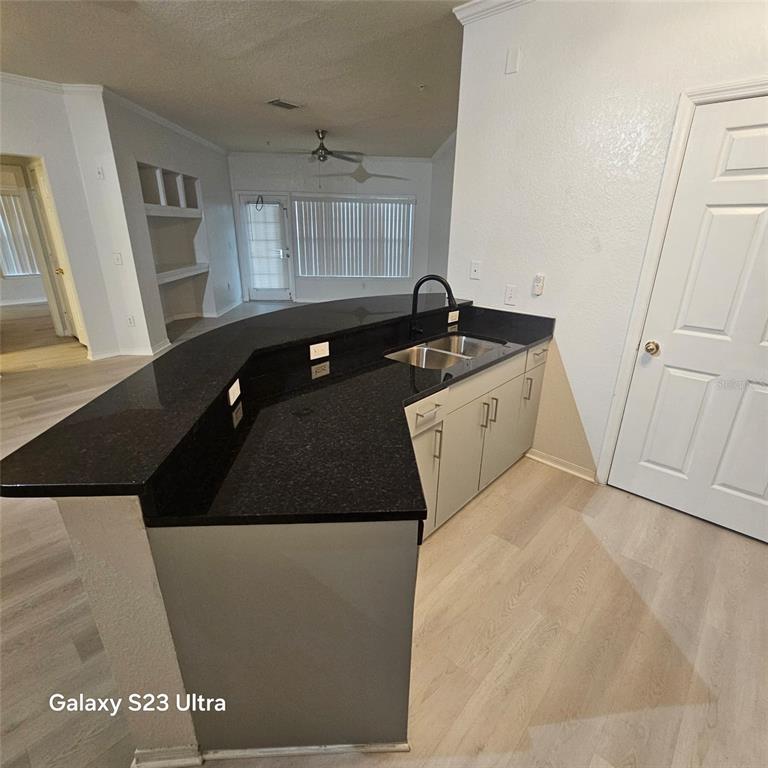 A kitchen island with a black granite countertop and a sink faces an open living area — 3621 CONROY ROAD UNIT 738, ORLANDO, FL