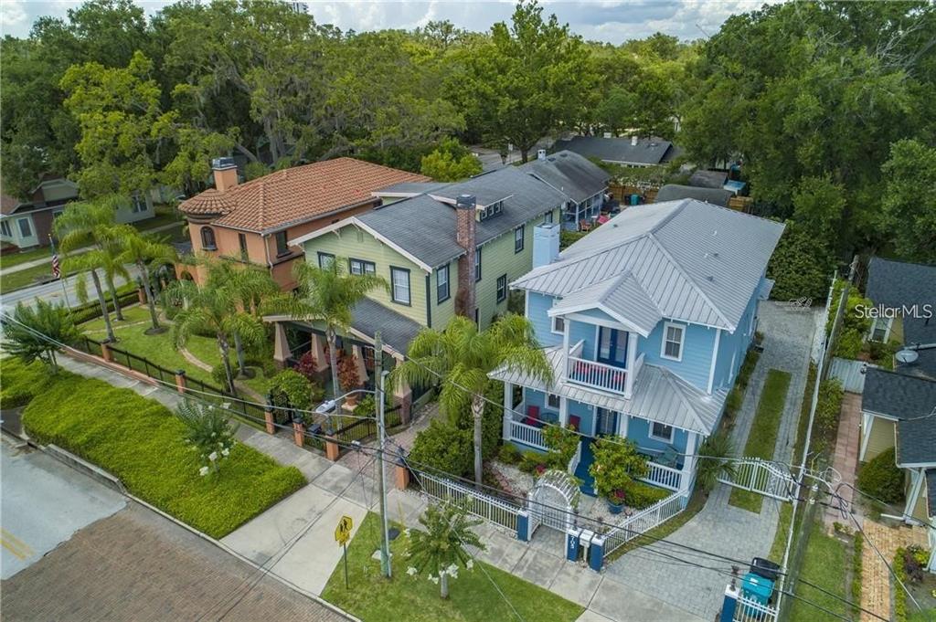 An aerial view shows three colorful houses with metal and shingle roofs along a street — 503 N SUMMERLIN AVENUE, ORLANDO, FL
