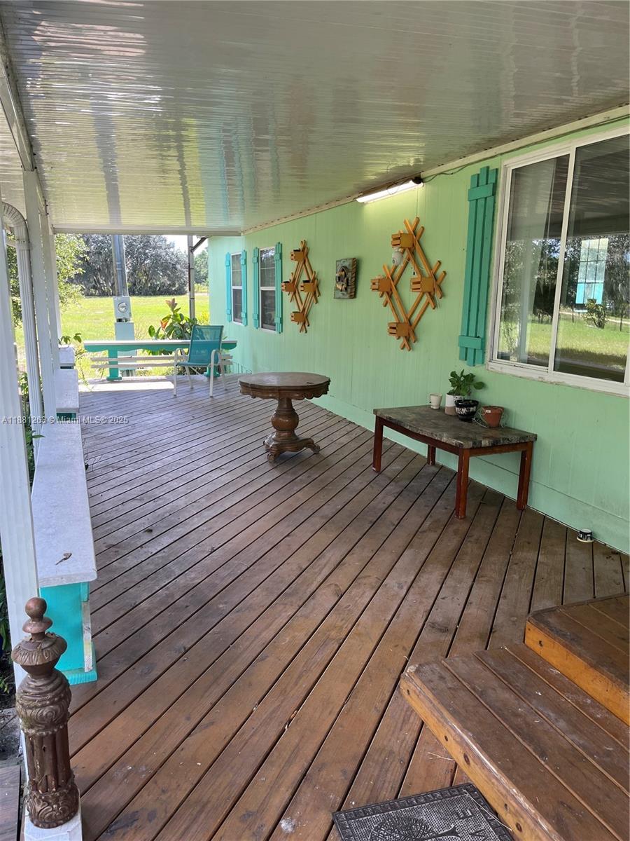 A wooden deck with a covered porch features a green wall and outdoor furniture — 105 Farrer RD, Frostproof FL 33843, FROSTPROOF, FL