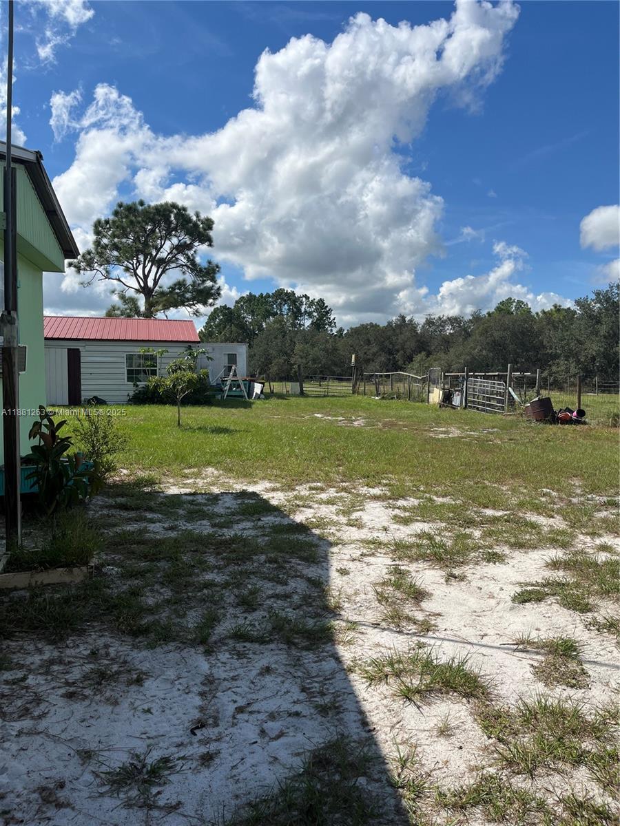 A grassy yard features a small white building with a red roof and fenced enclosures — 105 Farrer RD, Frostproof FL 33843, FROSTPROOF, FL
