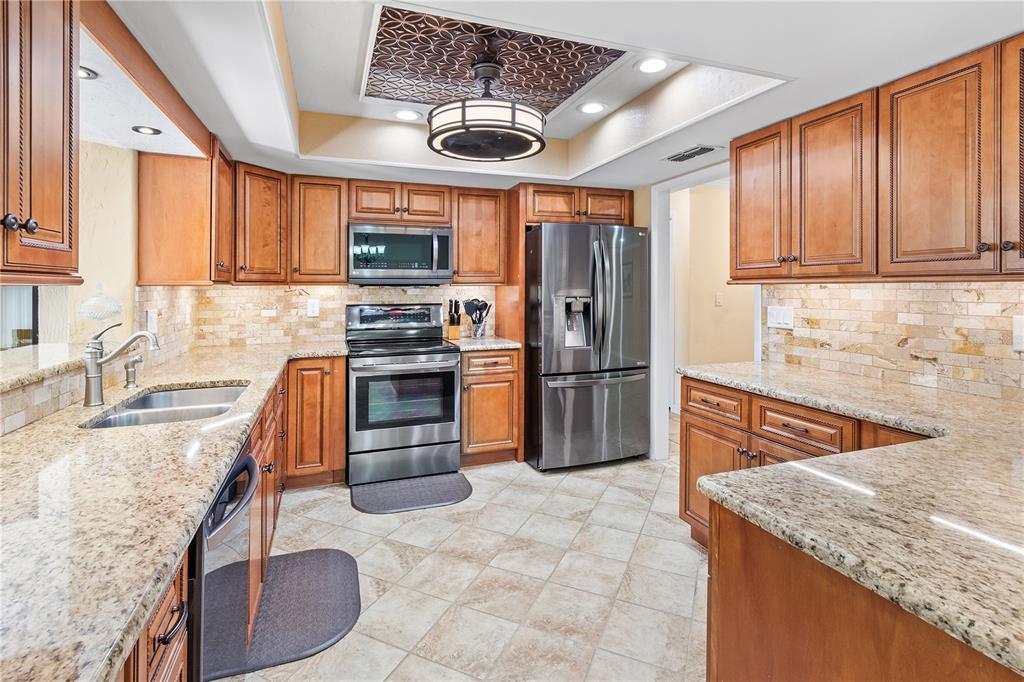 An open-concept dining area, kitchen with wood cabinets, and living room with neutral furniture — 731 CANBERRA ROAD, WINTER HAVEN, FL