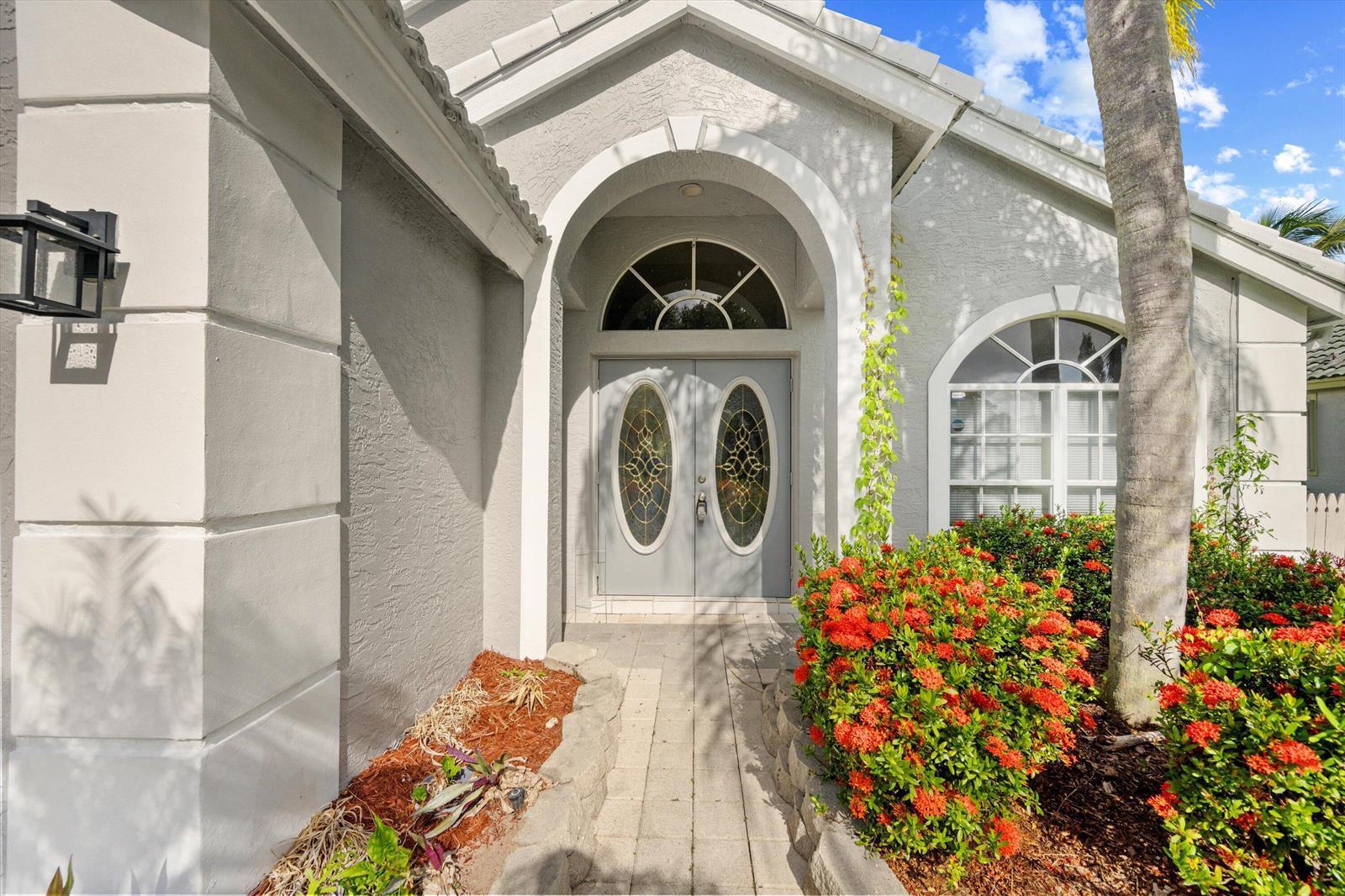 The exterior of a house features a gray double door entrance with arched glass inserts — 1851 Oak Berry Circle, Wellington FL 33414, WELLINGTON, FL