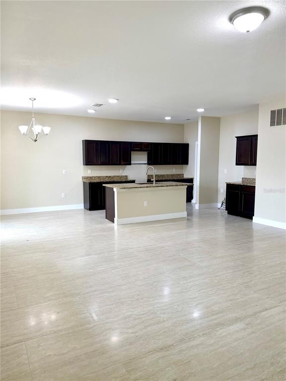 A kitchen features dark wood cabinets, granite countertops, a central island, and light tile flooring — 4669 OSPREY WAY, WINTER HAVEN, FL