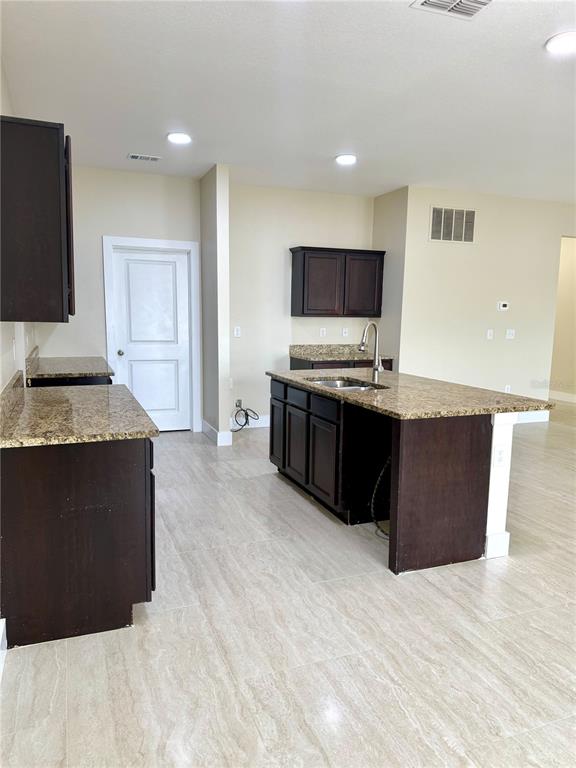 A kitchen features dark wood cabinets, granite countertops, and light-colored tile flooring — 4669 OSPREY WAY, WINTER HAVEN, FL