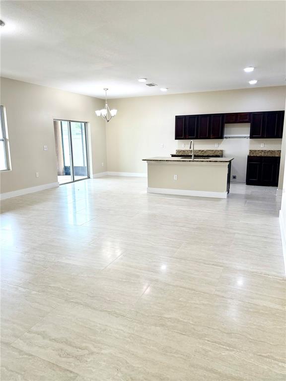 An open-concept kitchen and living area features dark wood cabinets and light tile flooring — 4669 OSPREY WAY, WINTER HAVEN, FL