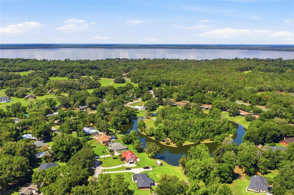 An aerial view shows houses nestled among trees near a winding pond and a large lake — 561 SE 28TH STREET, MELROSE, FL