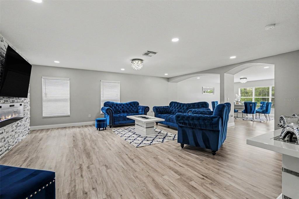 A living room features blue tufted sofas, a fireplace, and light wood-look flooring — 6222 CHERRY BLOSSOM TRAIL, GIBSONTON, FL