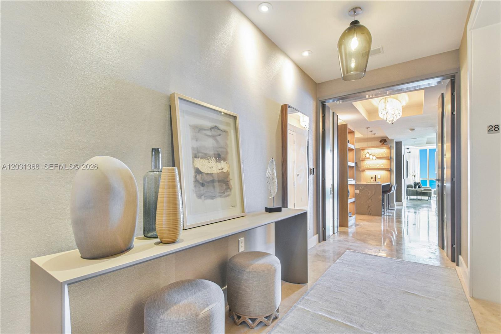 A modern entryway features a console table, two stools, and a view into a living area — 100 S Pointe Dr # 2806, Miami Beach FL 33139, MIAMI BEACH, FL