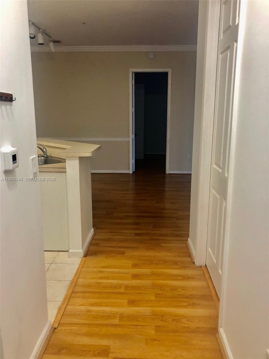 A hallway with wood flooring leads toward an open kitchen and a doorway — 4702 SW 160th Ave # 337, Miramar FL 33027, MIRAMAR, FL