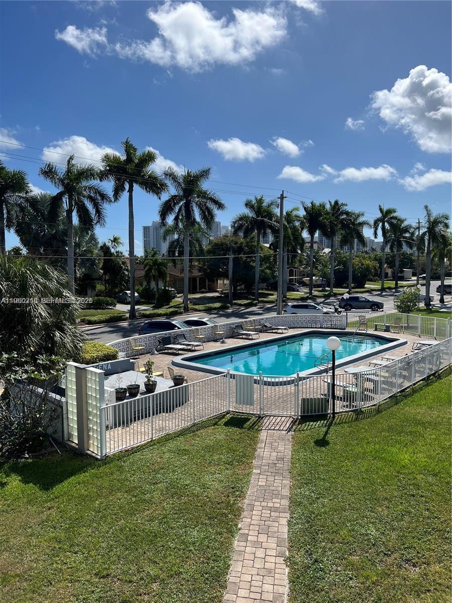 An outdoor swimming pool is surrounded by a white fence, lounge chairs, and palm trees — 600 Layne # 216, Hallandale Beach FL 33009, HALLANDALE BEACH, FL