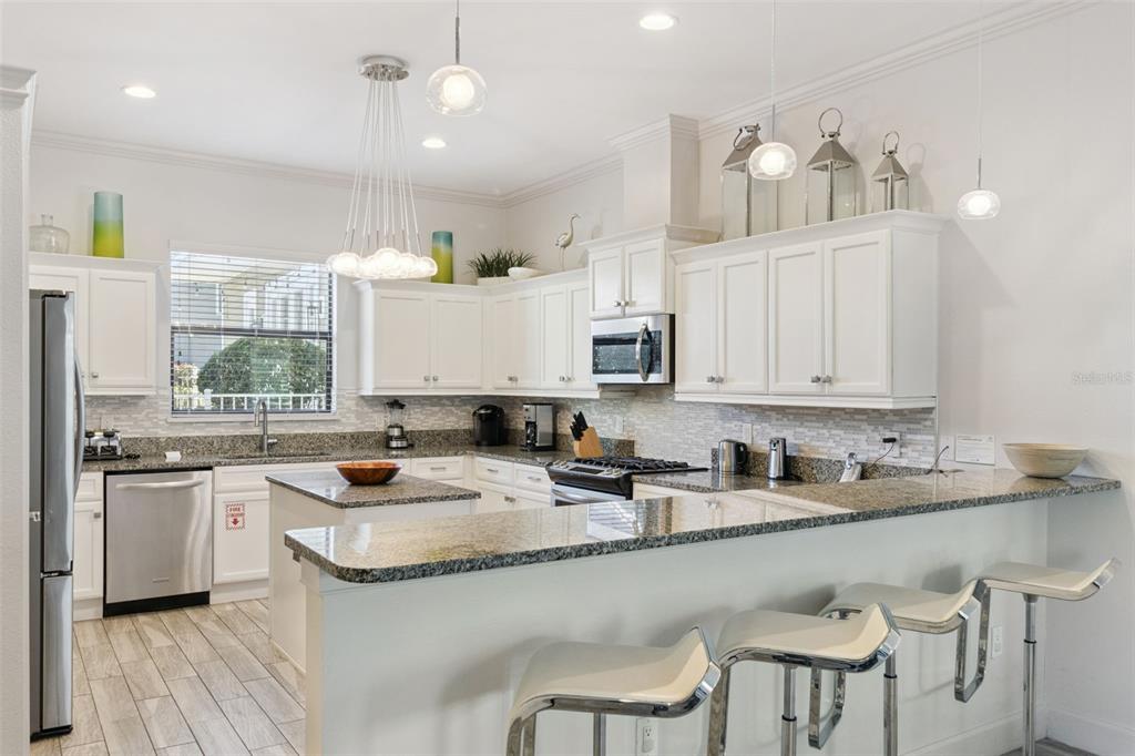 A kitchen features white cabinets, granite countertops, stainless steel appliances, and a breakfast bar — 7423 SPARKLING COURT, REUNION, FL
