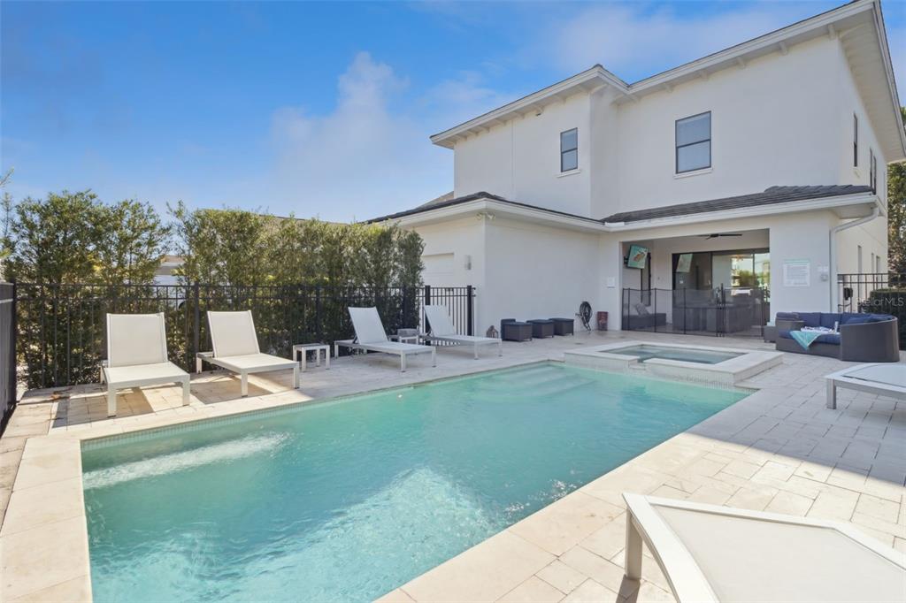 A backyard features a rectangular swimming pool, a hot tub, and several lounge chairs — 7423 SPARKLING COURT, REUNION, FL